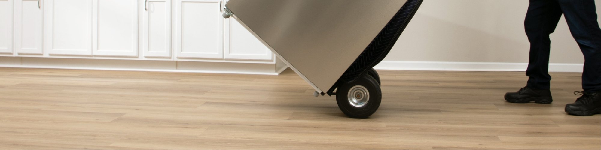 Moving a heavy fridge on a dolly across a durable vinyl floor